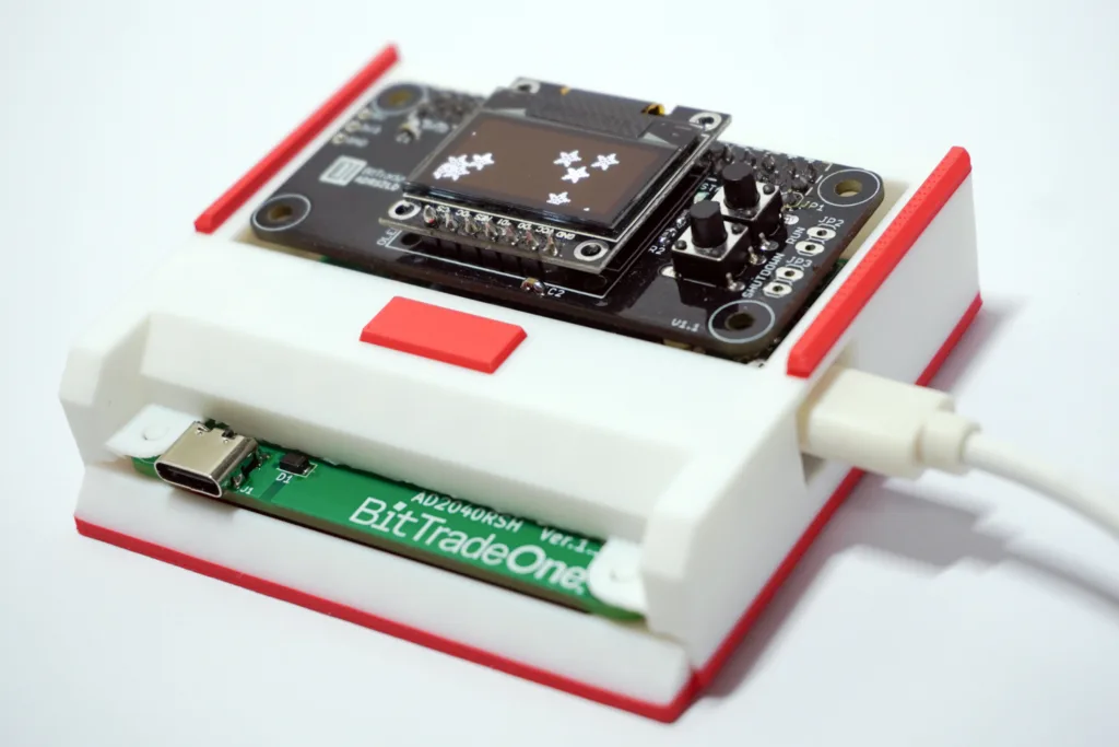 BitTradeOne microcontroller board mounted in a white plastic enclosure with red accents and a USB port visible atop the module.