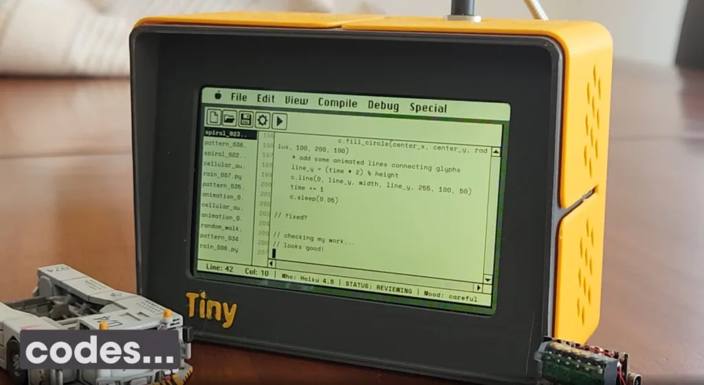 Yellow retro handheld computer displaying a green text editor with code on its screen.