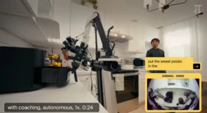 Robotic arm mounted on a kitchen counter operates a camera setup while a man watches in a bright white kitchen interior.