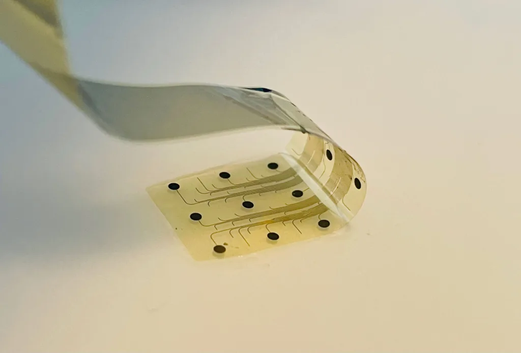 Close-up of a pale, perforated adhesive tape strip bent on a light surface.