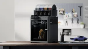 Modern multi-spool 3D printer on a wooden desk with a workshop backdrop and pegboard tools in the background.