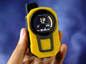 Handheld yellow lightning detector with a round display showing 10 km, 42 strikes, and energy metrics in view.