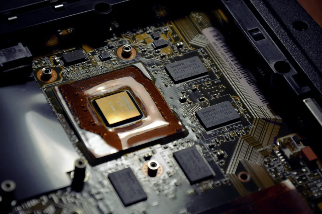 Close-up of a laptop motherboard with a copper heat sink and multiple chips and circuits visible inside the chassis.