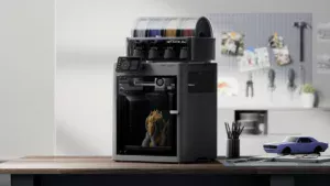 Modern multi-spool 3D printer on a wooden desk with a workshop backdrop and pegboard tools in the background.