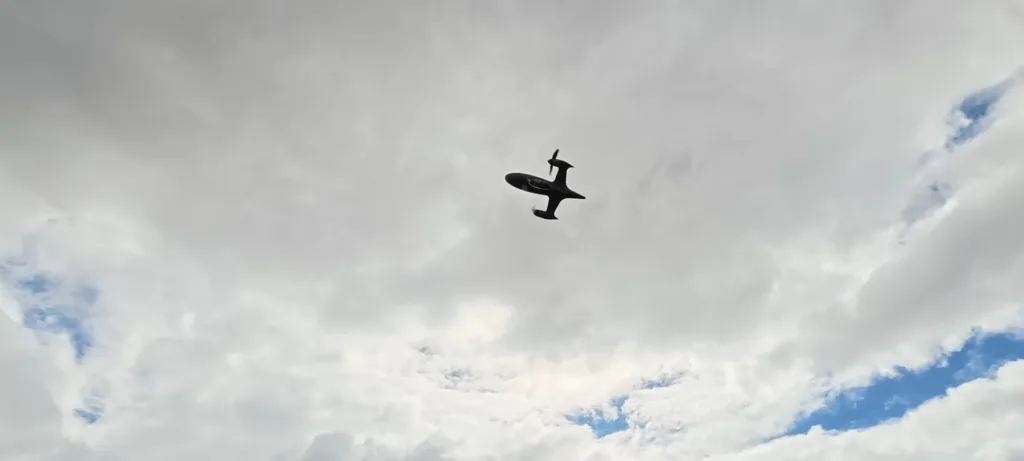 Small propeller airplane silhouetted against a gray, cloudy sky.