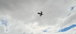 Small propeller airplane silhouetted against a gray, cloudy sky.