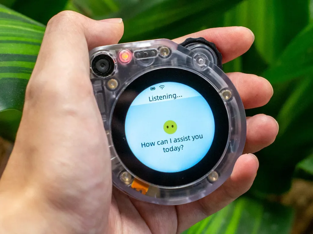 Transparent smartwatch held in a hand, screen showing 'Listening... How can I assist you today?' ready to respond to voice input