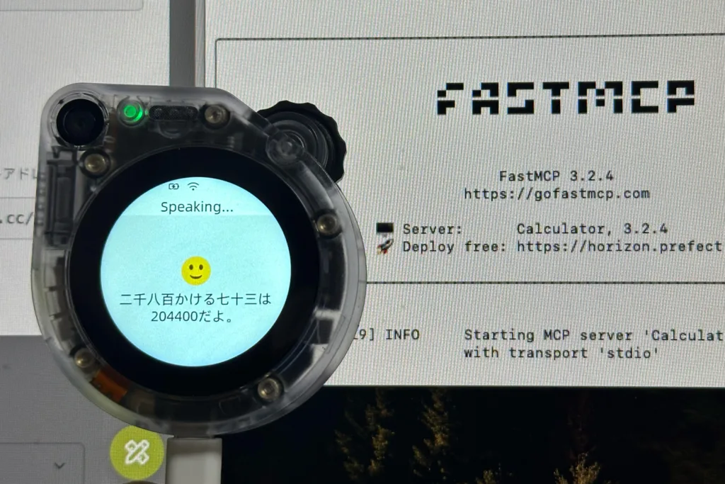 Clear round wearable device displaying 'Speaking...' with a smiley on a blue circle; background shows a terminal labeled FastMCP.