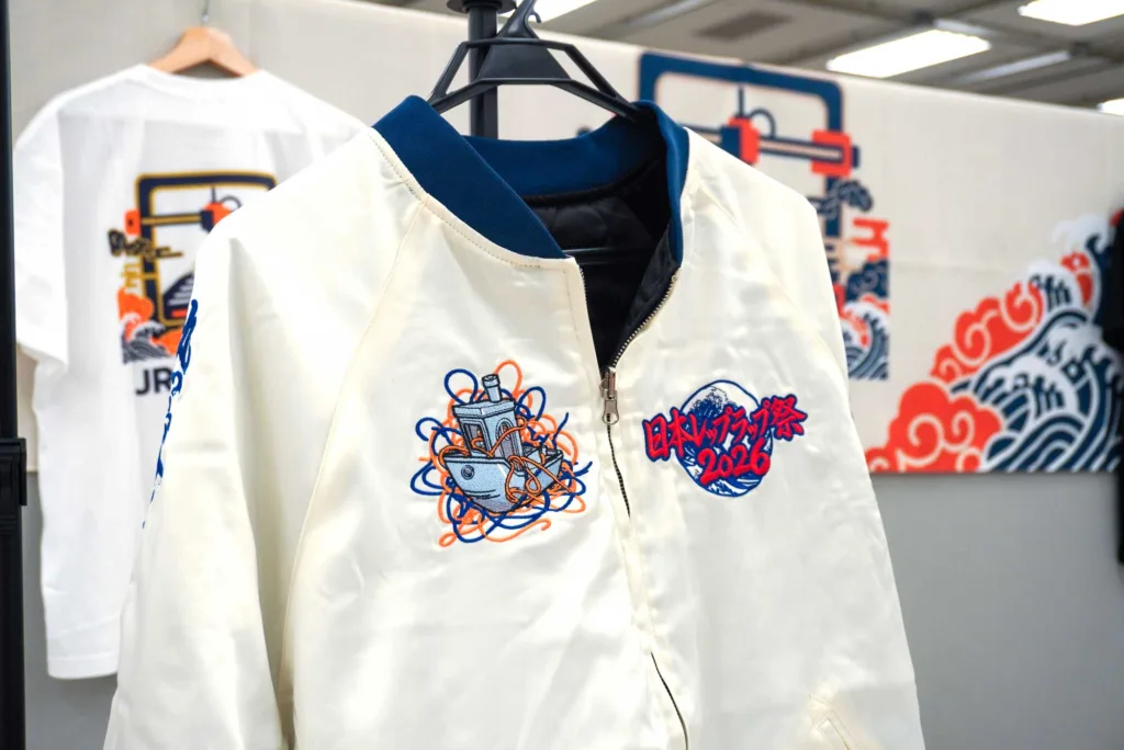 White jacket on a hanger with blue collar and colorful embroidery design including orange and blue elements.