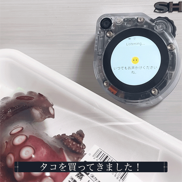 Transparent round voice-assistant device showing 'Listening…' beside a tray of octopus; caption in Japanese reads 'タコを買ってきました！'
