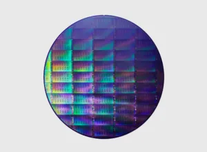 Close-up of a circular semiconductor wafer showing a colorful grid of silicon dies.