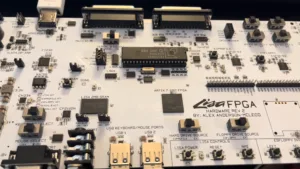 Close-up of a white FPGA development board with multiple connectors, chips, and labeled test points across the surface.