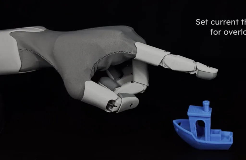 Robotic hand with articulated fingers pointing toward a blue plastic component on a black background.