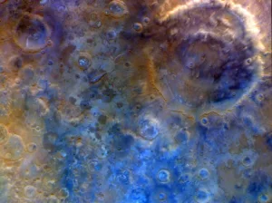 Close-up of the Moon's cratered surface in bluish-brown tones with many circular impact pits and ridges.