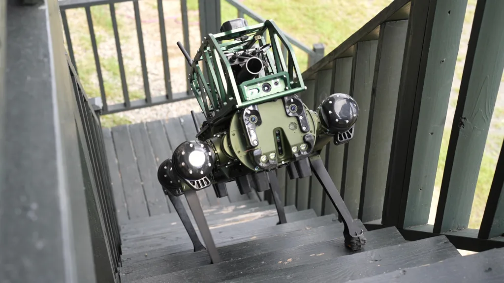 Green robotic camera rig with multiple lenses and sensors mounted on a wooden staircase outdoors.