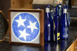 Framed decorative art: blue circle with three white stars on a white background, on a bar counter.