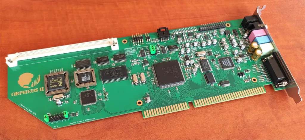 Orpheus II circuit board with edge connector, chips, capacitors, and a metal mounting bracket on a wooden surface