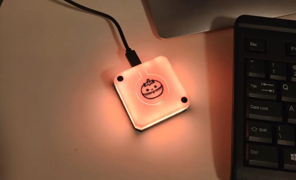 Pink, USB-powered square LED device glowing on a desk beside a laptop keyboard