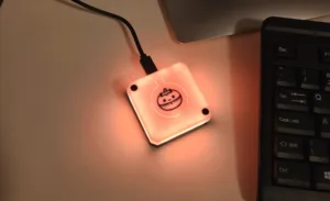 Pink, USB-powered square LED device glowing on a desk beside a laptop keyboard