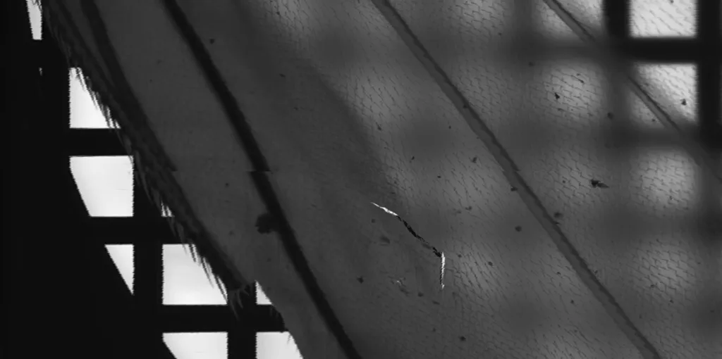 Close-up of a weathered, scratched metal surface with diagonal lines and black rectangular gaps on the left, creating an abstract industrial texture.