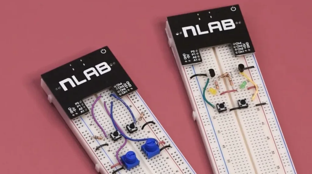 Two black NLAB microcontroller shields mounted on white breadboards connected with colored jumper wires, resistors, switches, and LEDs on a pink background.