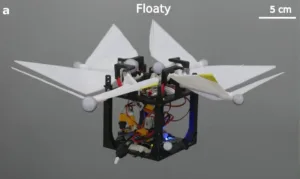 Quadcopter drone with four propellers and white origami-style wings, floating in midair against a gray backdrop.