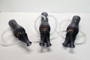 Three black medical-style breathing masks attached to clear flexible tubes, laid on a white surface.