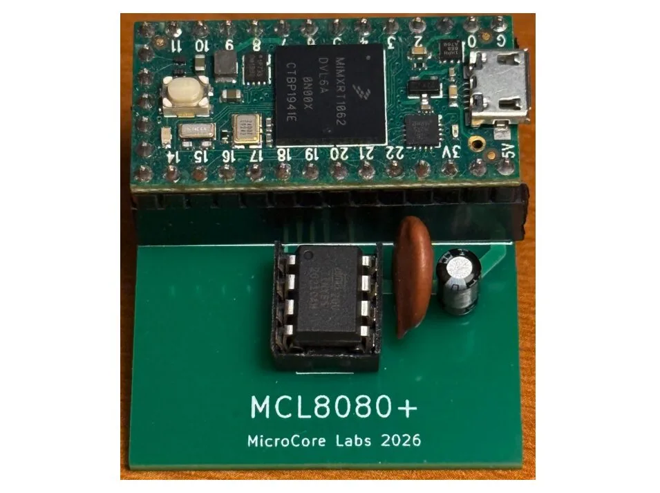 Close-up of an MCL8080+ MicroCore Labs development board; green base with a USB micro connector, a black IC socketed module, a brown capacitor, and the text 'MCL8080+ MicroCore Labs 2026' visible on the board.