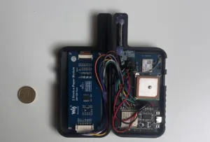 Internal view of a small handheld device showing a blue 2.9-inch e‑Paper module on the left and a crowded motherboard with wires on the right; a coin sits beside for scale.