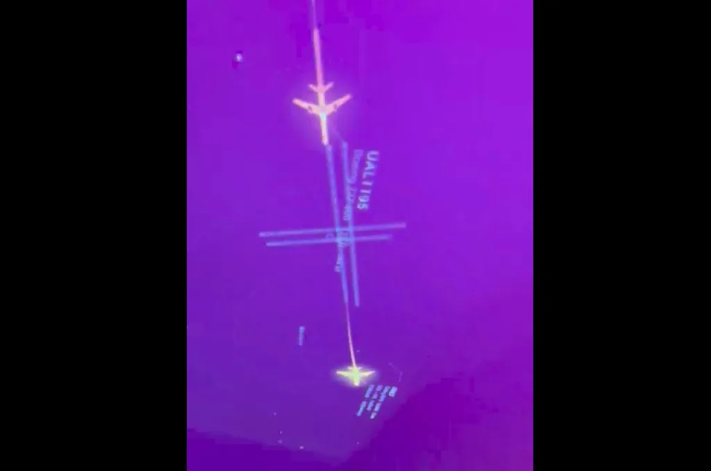 Infrared image showing a small airplane icon aligned with a vertical axis and crosshair marks against a purple background, suggesting a targeting/alignment display.