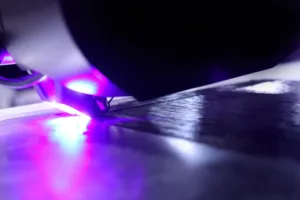 Close-up of a vinyl record on a turntable with purple-blue LED lighting, capturing a glimmering reflective surface and stylus.
