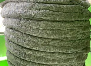 Coiled thick green rope with a pebbled surface, stacked in rings against a green background.