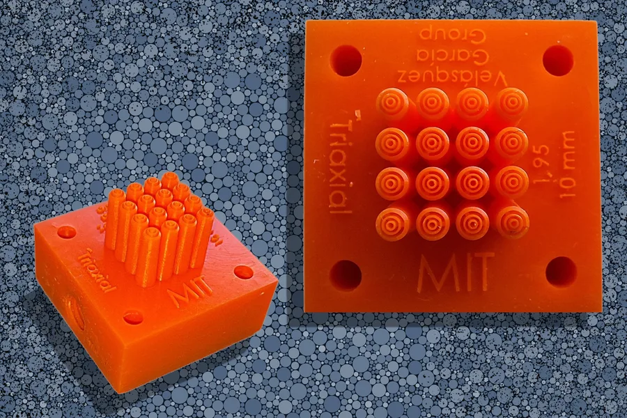 Orange silicone block with a 4x4 grid of small cylindrical pins; shown from a side angle and a top view with 'MIT' molded on the surface.