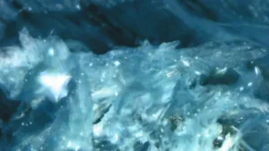 Close-up of blue ice crystals and flowing water, with a frosty, crystalline texture.