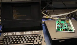 Retro computer workstation with a CRT monitor displaying green text and a green circuit board to the right.