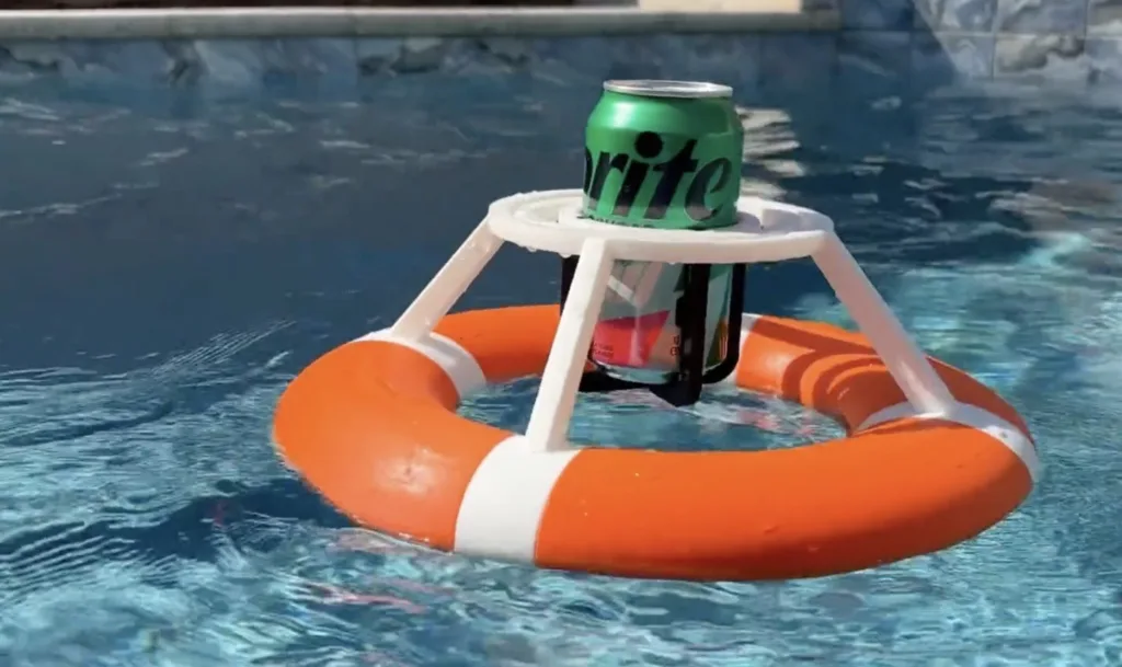Green Sprite can resting on a small white plastic frame above an orange lifebuoy floating in a swimming pool