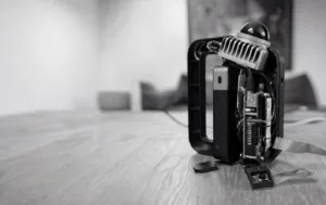 Exposed electronic device with circuit boards and cables on a wooden floor (black-and-white photo).